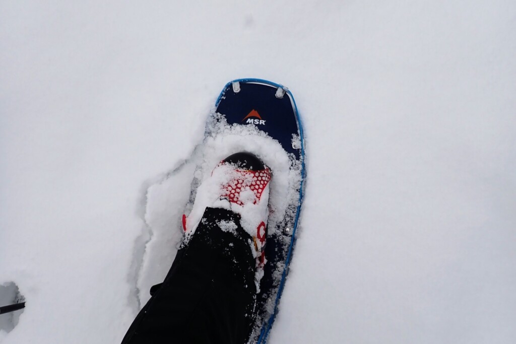 スノーシューを装着して深雪の冬山を歩く登山者の足元