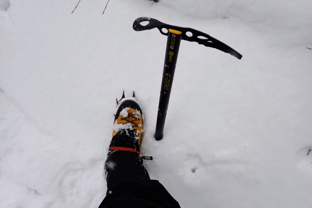 冬山でアイゼンとピッケルを装着した登山者の足元