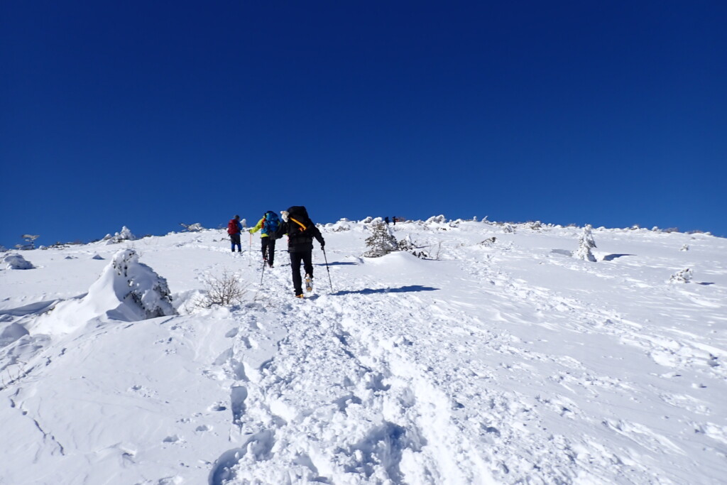 安達太良山山頂へ続く冬の登山道を歩く登山者たち