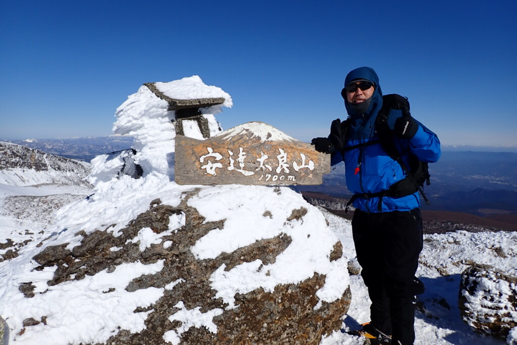 厳冬期、安達太良山山頂で強風で寒い中で記念写真をとる筆者