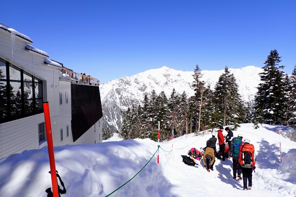 新穂高ロープウェイ西穂高口駅を出た登山者と穂高連峰の雪景色