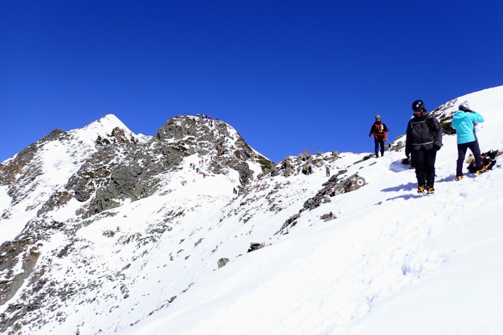 西穂独標直下の雪稜を歩く登山者