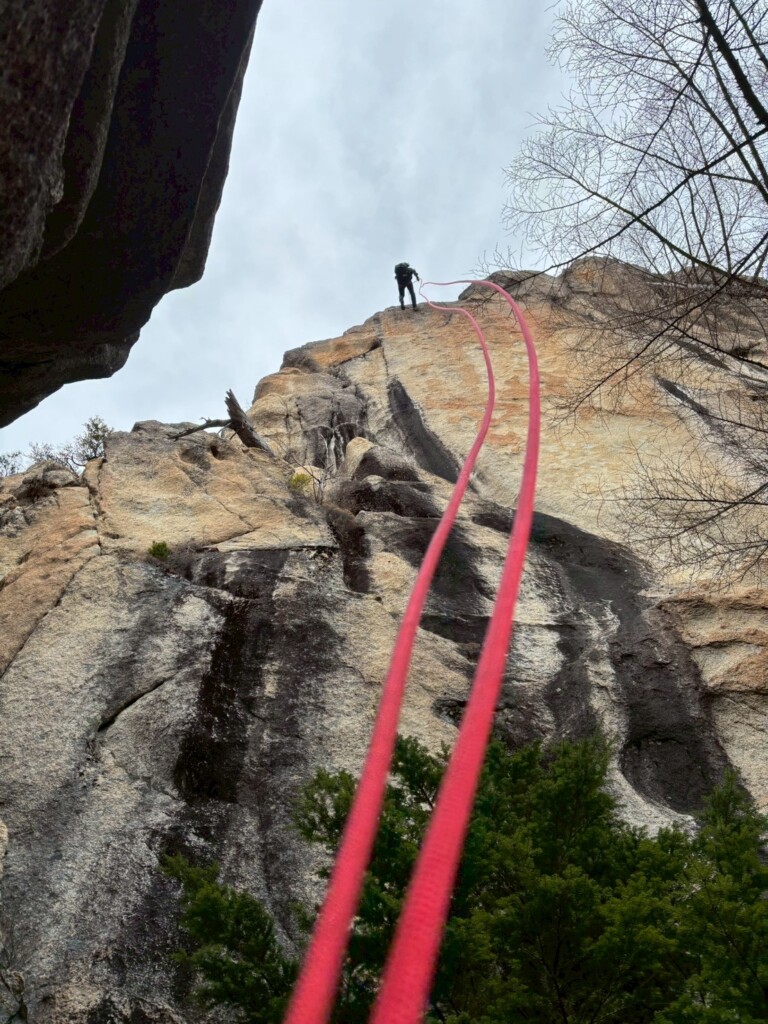 小川山の岩壁で赤いロープを使って懸垂下降するクライマー