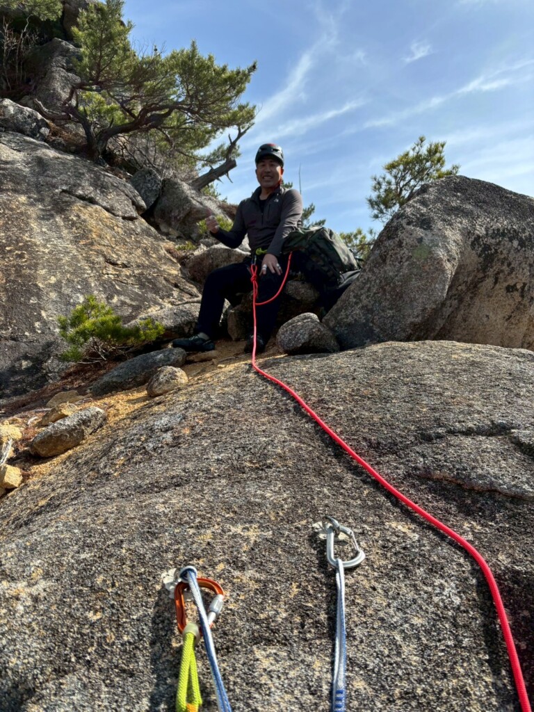 岩棚でロープをつないだまま休憩するクライマー