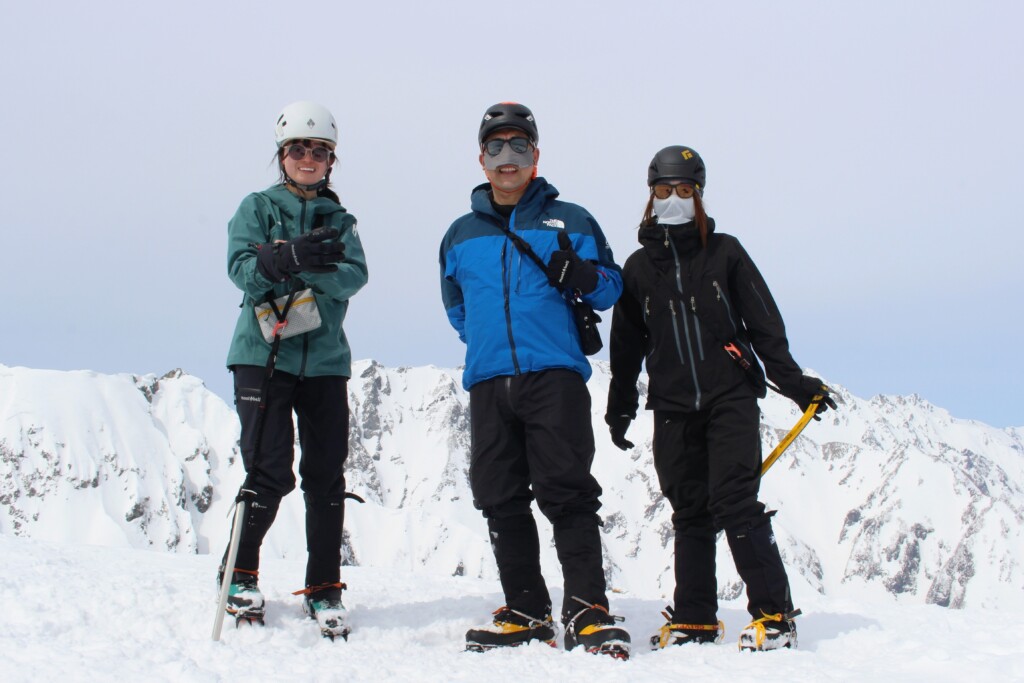 残雪期の八方尾根を背景に撮影した下山途中の記念写真
