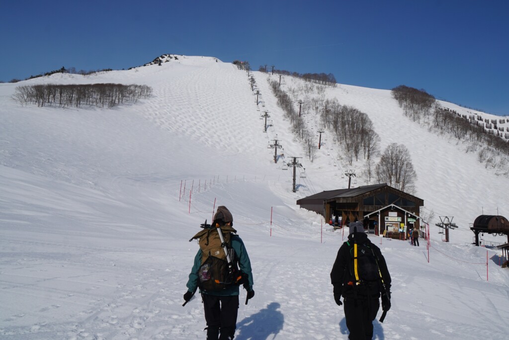八方尾根スキー場でゴンドラを降りてリフト乗り換えへ向かう登山者2人