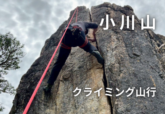 Climber wearing a harness ascends a rocky cliff with a bright red rope; Japanese text '山小川' and 'クライミング山行' overlay the image.